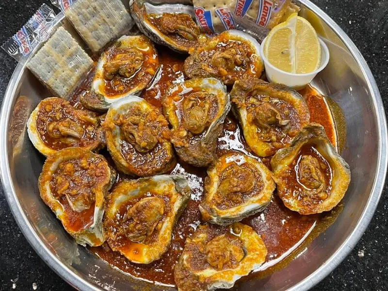 Spicy sauce topped oysters with crackers at Sup Crab Pompano Beach, a Seafood Restaurant in Pompano Beach